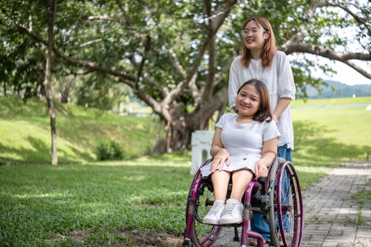 Young Woman in Wheelchair Enjoying a Park Stroll with Her Best Friend on a Sunny Day photo