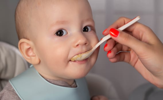Mother feeds baby boy vegetable puree from a spoon. Feeding children 7 months. Close-up photo
