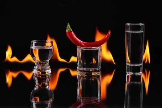 A glass with a chili pepper and a shot glass photo