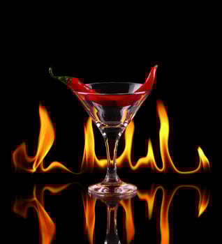 Hot chili pepper in a martini glass with a fire on a black background photo