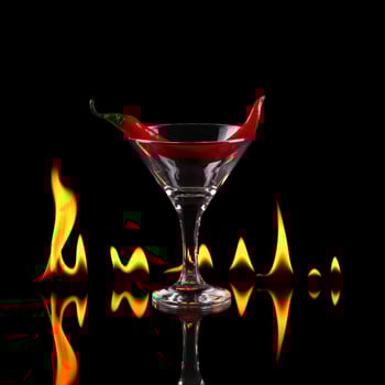 A martini glass with a red chili pepper in it, black background photo
