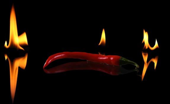 Hot pepper with flame on black background photo