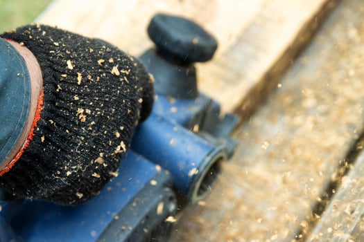 A man works with an electric tool with an electric planer, cleans old wood. Industry, close-up photo