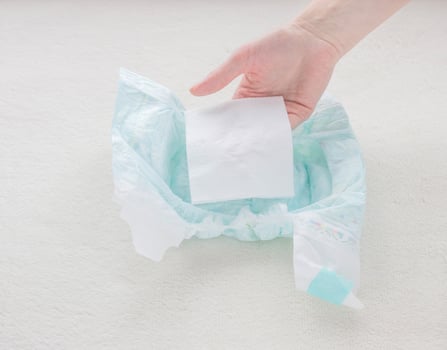 The girl checks the absorbency of a baby nappy with a napkin, close-up photo