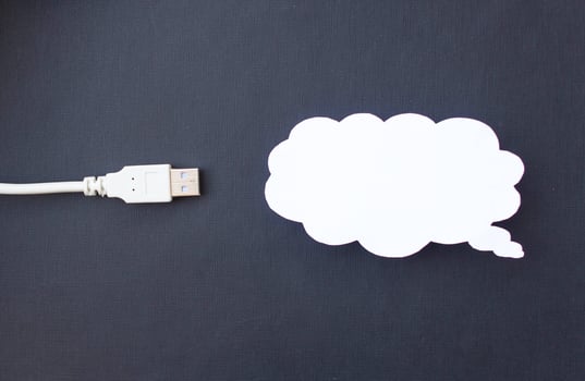 Cloud for data storage cut from paper on a black background and cable usb, close-up, data storage on the Internet photo