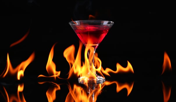 Hot chili pepper in a martini glass with a fire on a black background photo
