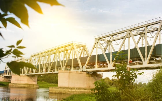 The freight train is moving along the railway bridge across the river photo