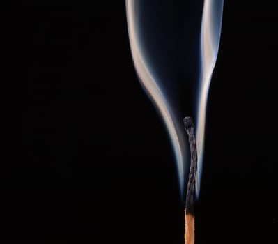 Burned match with clouds of smoke on a black background photo