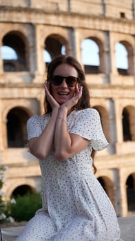 Cheerful woman in sunglasses enjoying her visit at the Colosseum in Rome, Italy photo