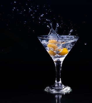 A martini glass with water splashing on top of it, darl background photo