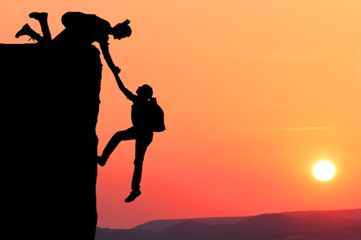 Teamwork couple hiking help each other trust assistance silhouette in mountains, sunset. Teamwork of man and woman hiker helping each other on top of mountain climbing team, beautiful sunset. photo