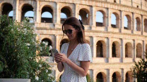 Woman in dress using phone near the Colosseum in Rome, Italy, on a sunny day photo