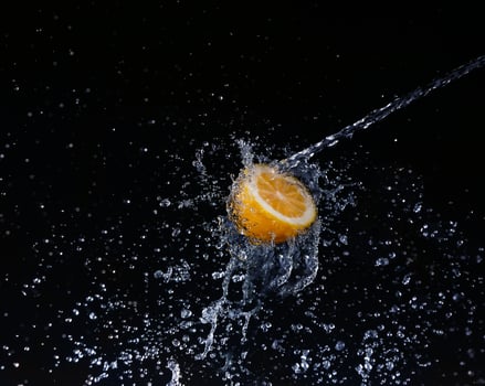 A high-speed shot of a lemon with splashing water, on a black background. photo
