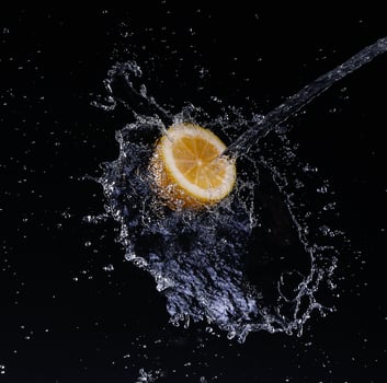 A high-speed shot of a lemon with splashing water, on a black background. photo