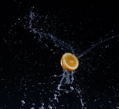 A high-speed shot of a lemon with splashing water, on a black background. photo