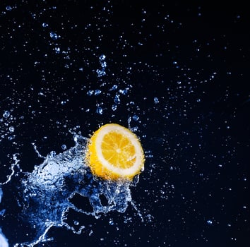 Lemon into water splash on black background photo