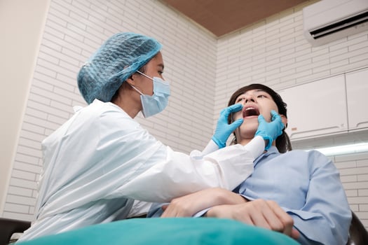 Asian female dentist examine young male patient teeth and toothache stomatology in dental clinic, well-being hygiene checks, and professional orthodontic healthcare work in doctor's office hospital. photo