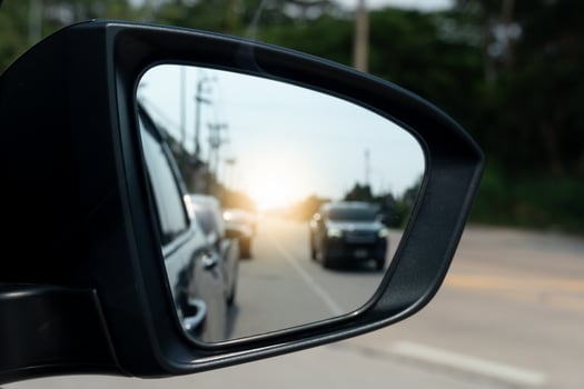 Driving traffic of cars seen through the side mirrors. Blurred of concrete road with dark trees side of road. photo