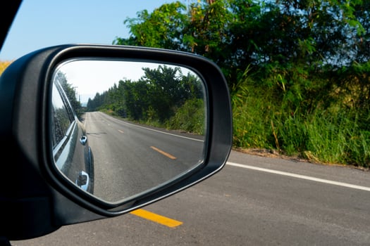 Inside view of mirrors wing. Rear view of a gray car with asphalt road. photo