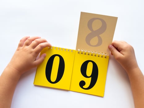 Childs hands flipping calendar to number nine on white background photo