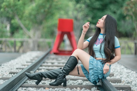 A woman sitting on a railroad track with her hand on her mouth photo
