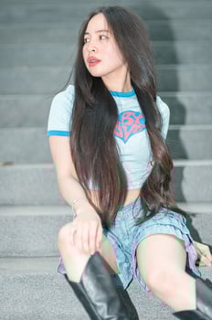 A woman sitting on some steps wearing a blue shirt and black boots photo