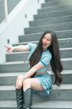 A woman in a blue shirt and black boots sitting on some stairs photo