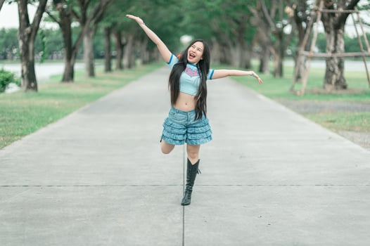 A woman in a blue shirt and skirt is jumping in the air photo
