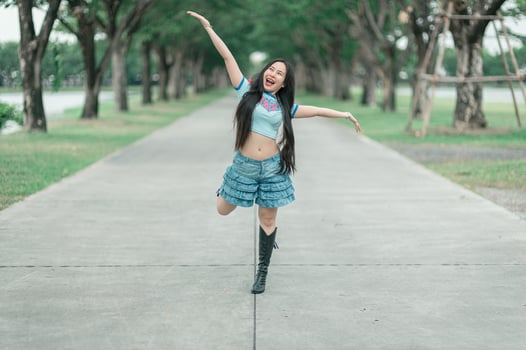 A woman in a blue shirt and skirt dancing in the park photo
