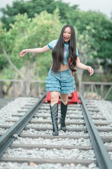 A woman in a blue shirt and short skirt is walking on the railroad tracks photo