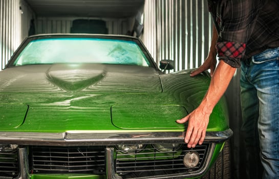 Restoring a Vintage Green Car in a Storage Container on a Sunny Afternoon photo