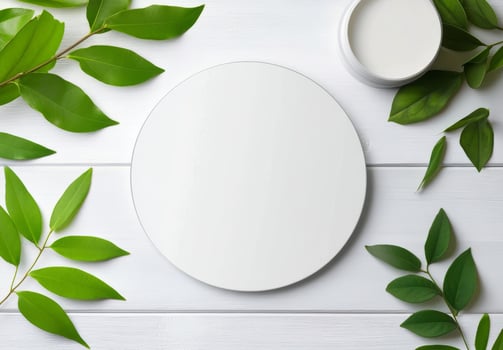 Circular white plate surrounded by vibrant green leaves on a light wooden surface photo
