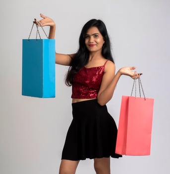 Beautiful young girl holding and posing with shopping bags on a grey background photo