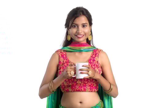 Beautiful young girl with cup of tea or coffee posing on white background photo