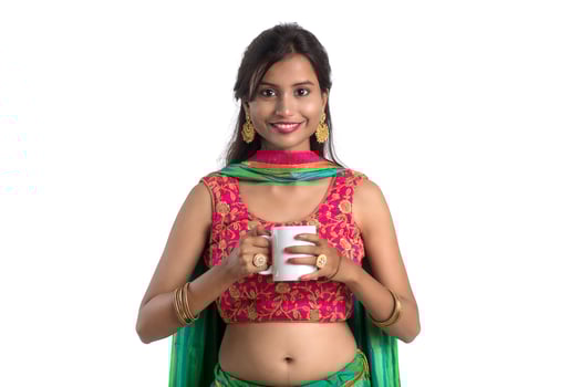 Beautiful young girl with cup of tea or coffee posing on white background photo