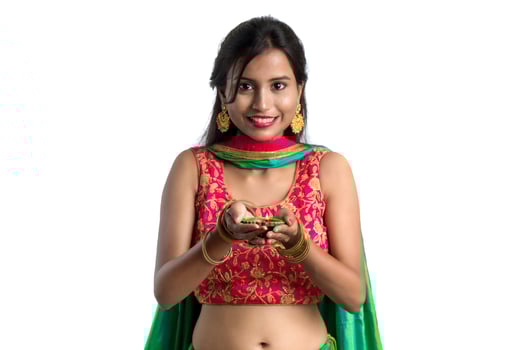 Portrait of a Indian Traditional Girl holding Diya, Girl Celebrating Diwali or Deepavali with holding oil lamp during festival of light on white background photo