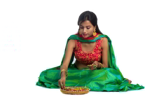 Portrait of a Indian Traditional Girl holding Diya and making Rangoli. Girl Celebrating Diwali or Deepavali with holding oil lamp during festival of light on white background photo