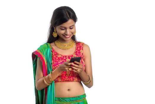 Young Indian traditional girl using a mobile phone or smartphone isolated on a white background photo