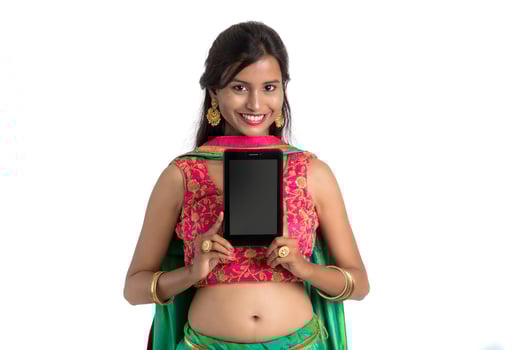 Young Indian traditional girl using a mobile phone or smartphone and showing blank screen smart phone on white background photo