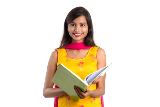 Pretty young girl holding book and posing on white background photo