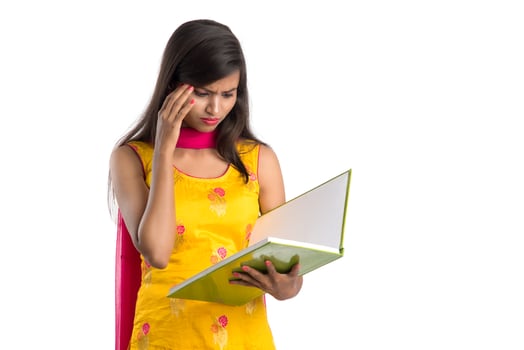Pretty young girl holding book and posing on white background photo