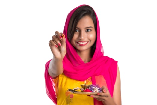 Beautiful Indian young girl holding pooja thali or performing worship on a white background photo