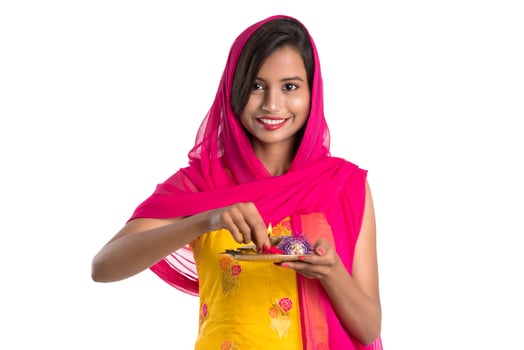 Beautiful Indian young girl holding pooja thali or performing worship on a white background photo