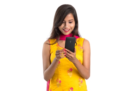 Young Indian girl using a mobile phone or smartphone isolated on a white background photo