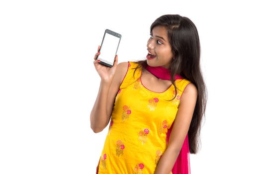 Young beautiful woman holding and showing blank screen smartphone or mobile or tablet phone on a white background. photo
