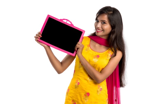 Beautiful young girl holding and showing something on a chalkboard or slate, isolated over white background photo
