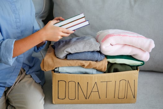 The girl puts clothes in donation box photo