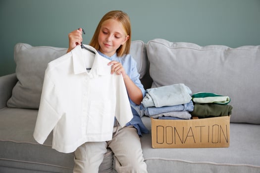 The girl puts clothes in donation box photo