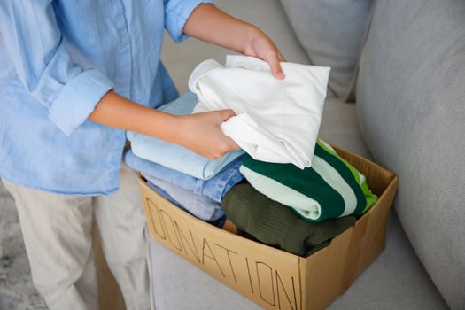 The girl puts clothes in donation box photo