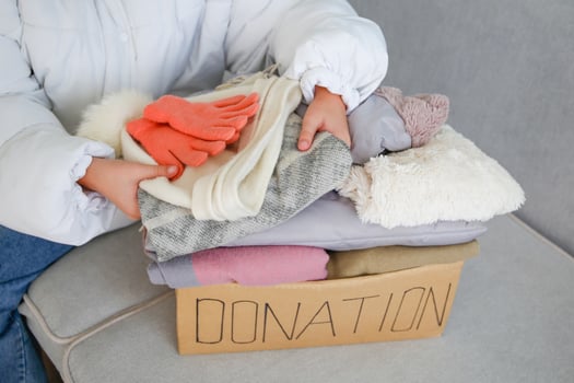 A child holds a donation box with clothes in the living room. photo